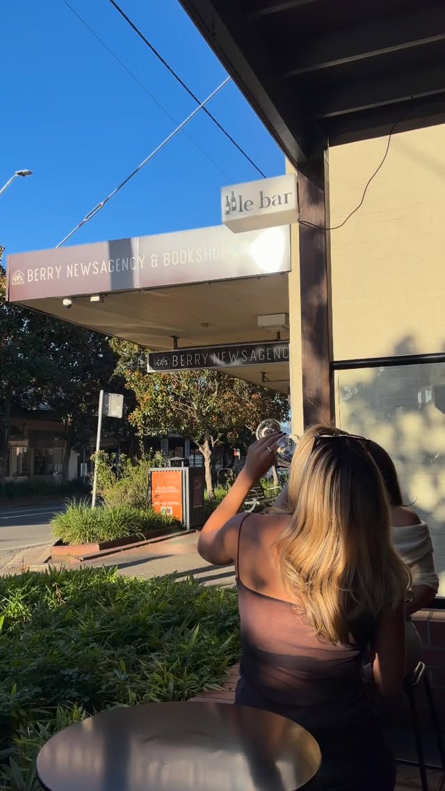 A guest sipping wine under the le bar. sign